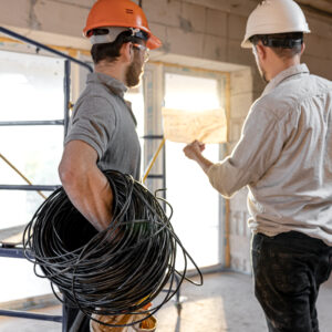 Two builder engineers talking at building site, engineer explaining a drawing to a worker.