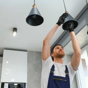 A male electrician changes the light bulbs in the ceiling light. men's household duties. care of electrical appliances at home.